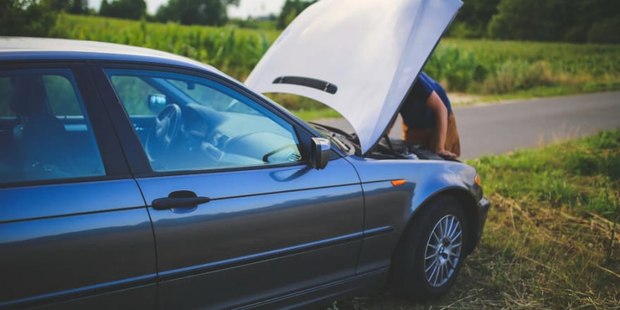 A car with the hood up while a man looks inside